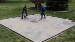 spreading polymeric sand across surface of paver patio
